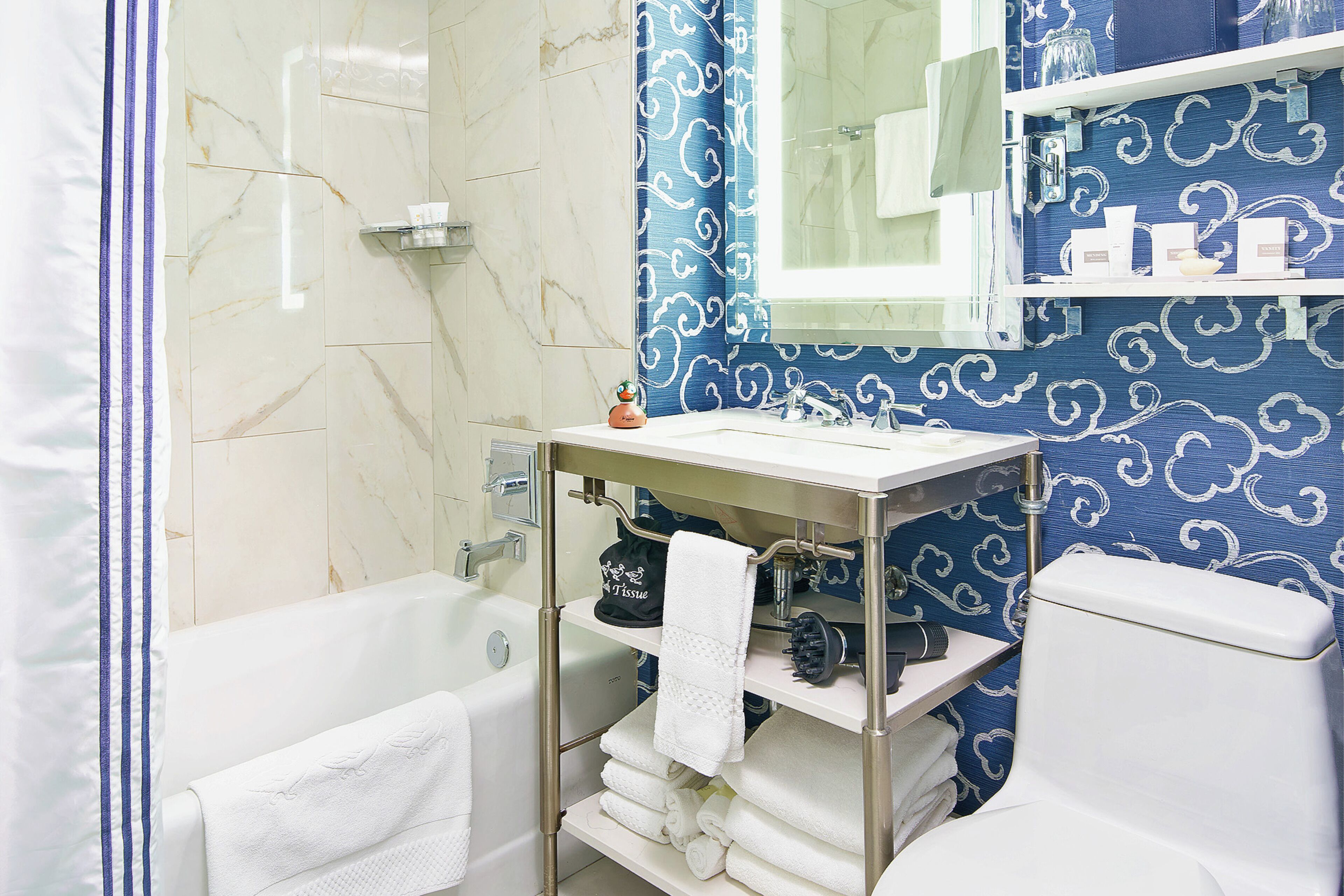 A bathroom with a bathtub, a sink with a towel rack, and a toilet.