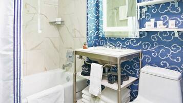 A bathroom with a bathtub, a sink with a towel rack, and a toilet.