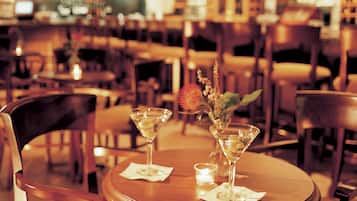 A restaurant interior with round tables, chairs, and a bar in the background.
