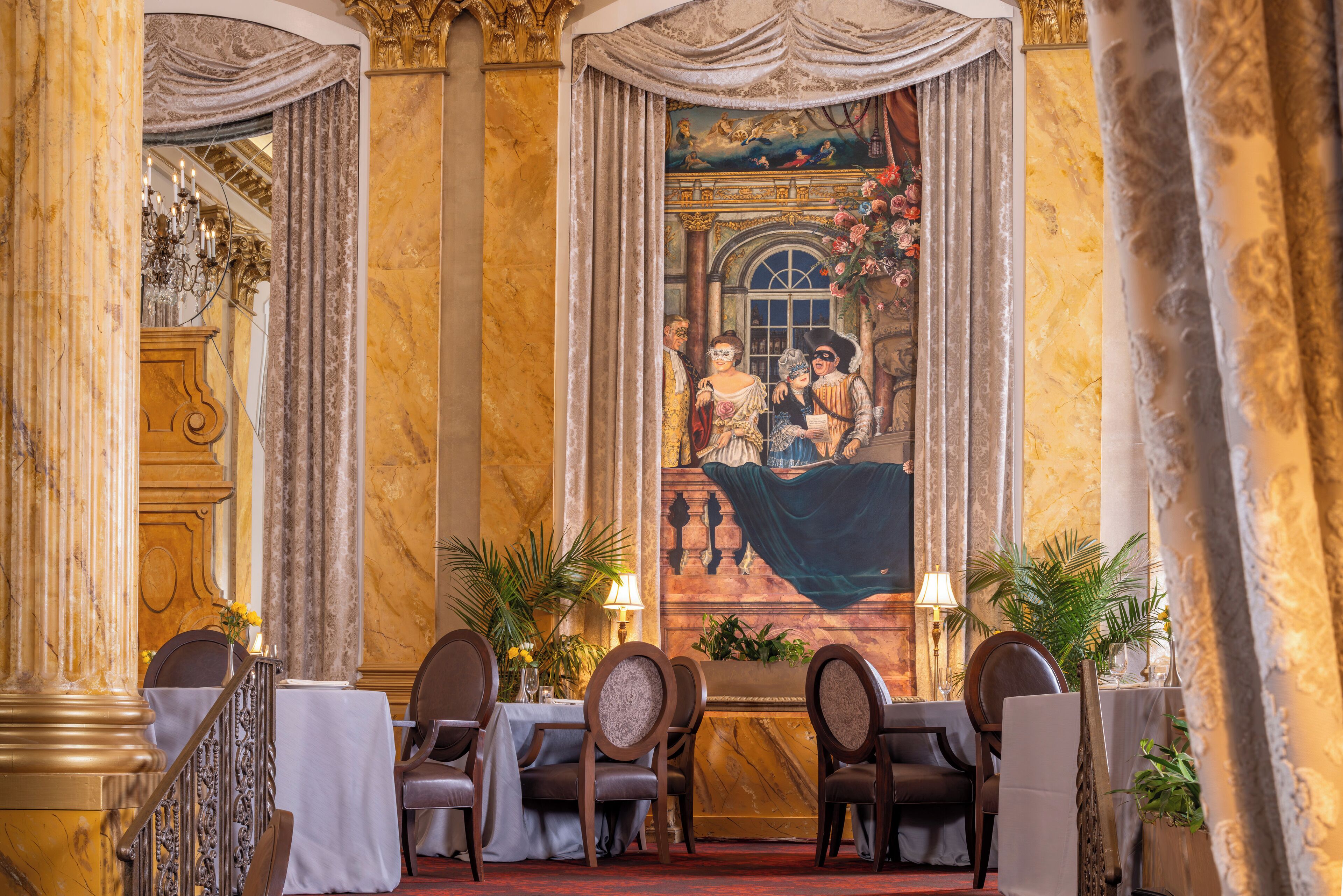 Un comedor lujoso con paredes de mármol, candelabros ornamentales y obras de arte clásicas.