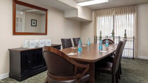Un salón de conferencias con una larga mesa, sillas, un armario y un espejo grande.