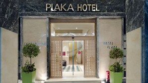 La entrada al hotel Plaka, con un piso de diseño a cuadros y dos plantas en macetas.