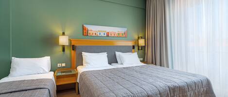 A hotel room with two beds, a painting on the wall, and a window with curtains.