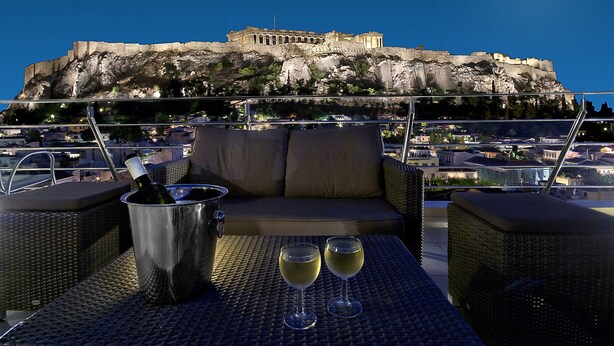 Terraza en la azotea con vista a un edificio histórico, una botella de champán y dos copas sobre una mesa.