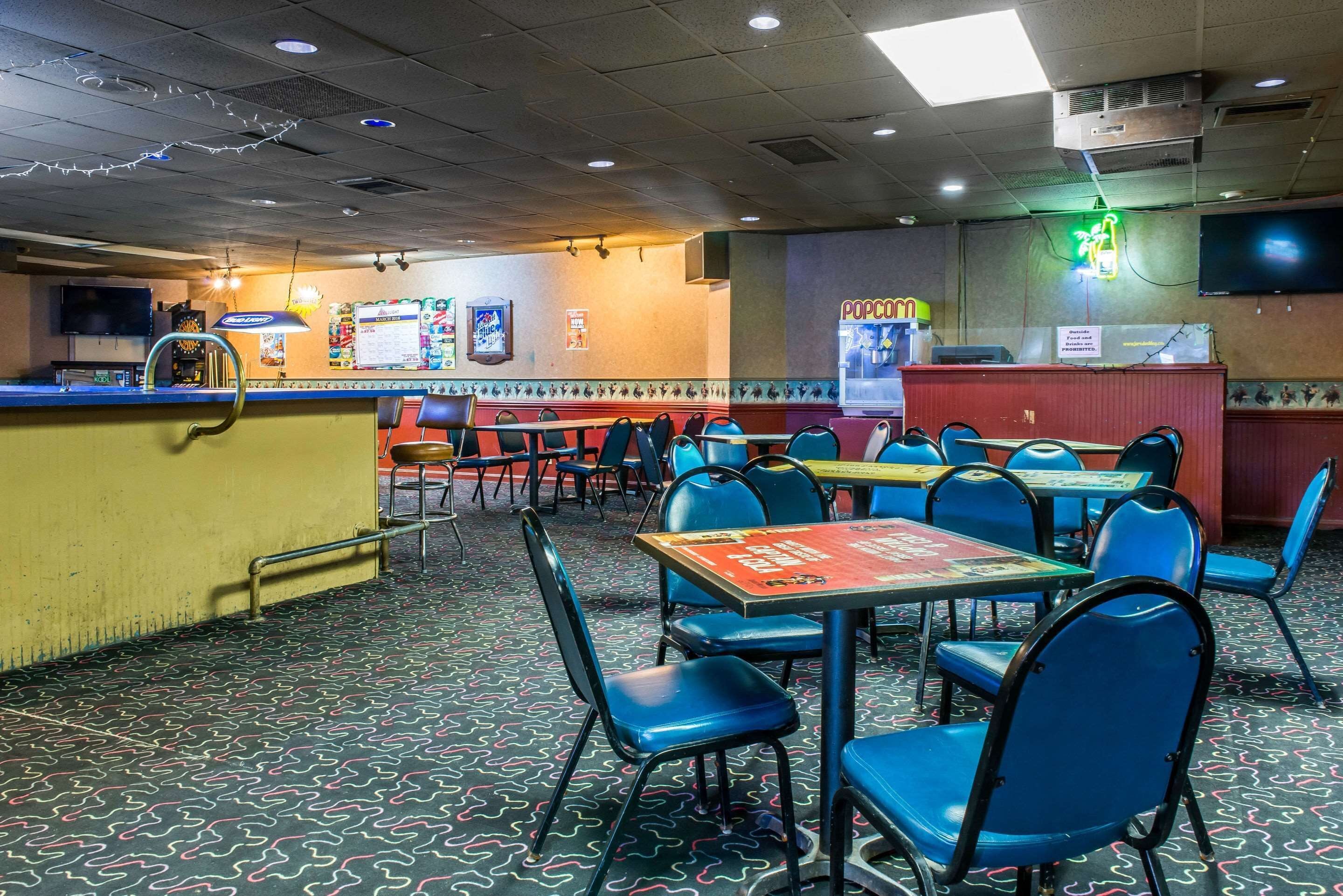 A restaurant interior with tables and chairs, a counter, and a neon sign.