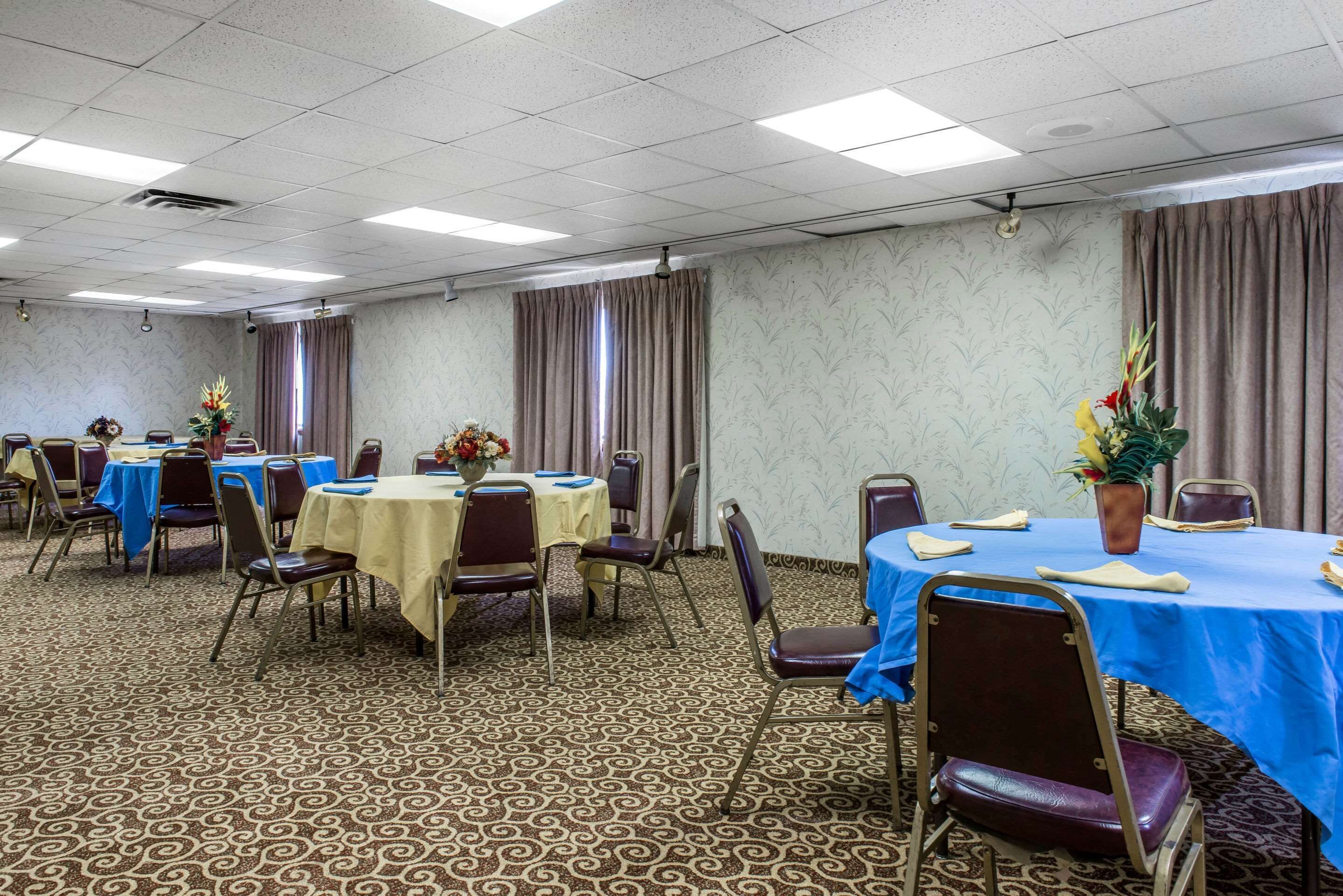 A conference room with multiple tables and chairs, arranged in rows.