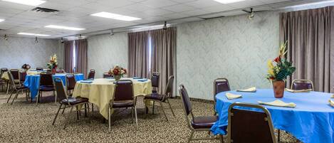 A conference room with multiple tables and chairs, arranged in rows.
