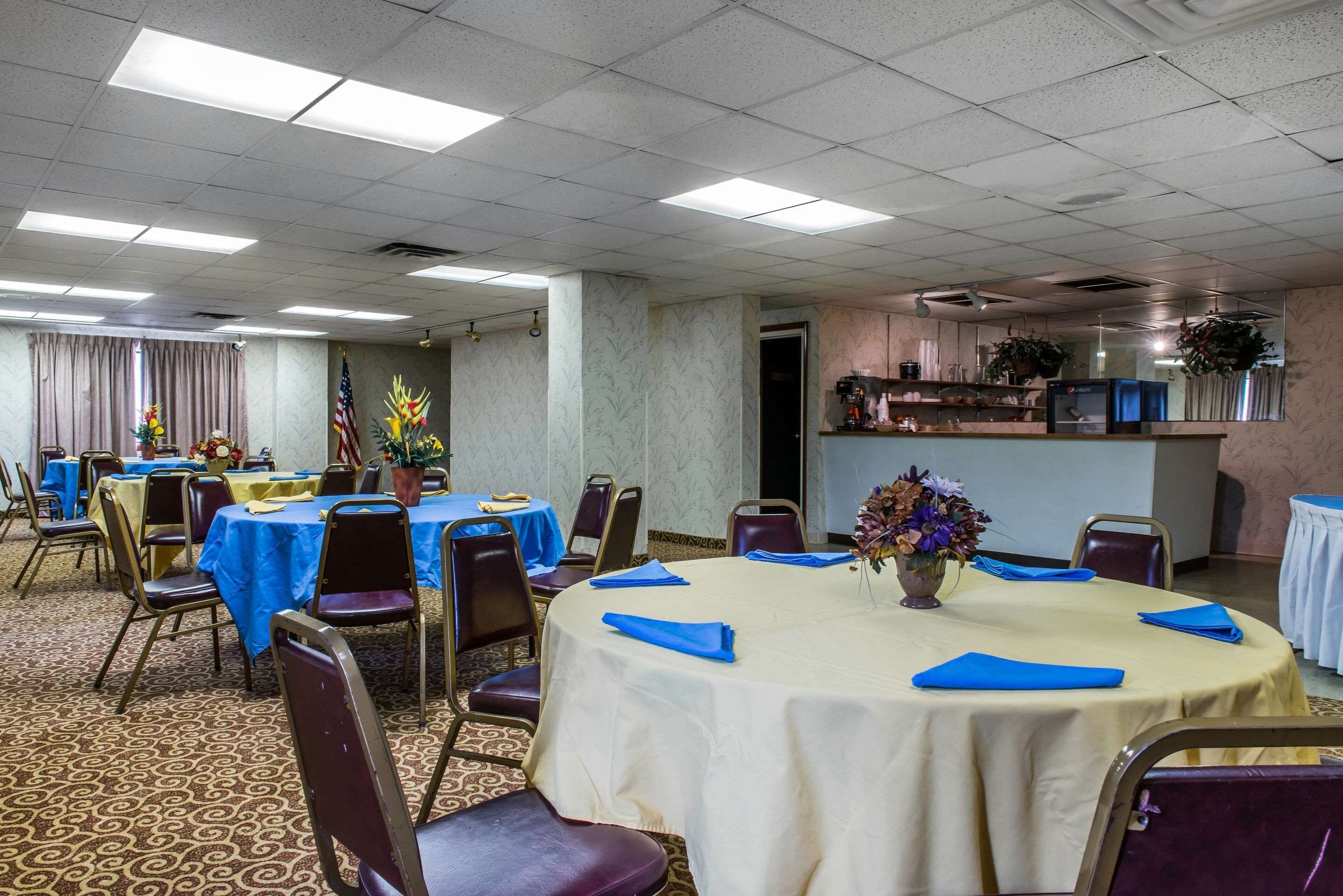 A conference room with round tables, chairs, and a buffet area.
