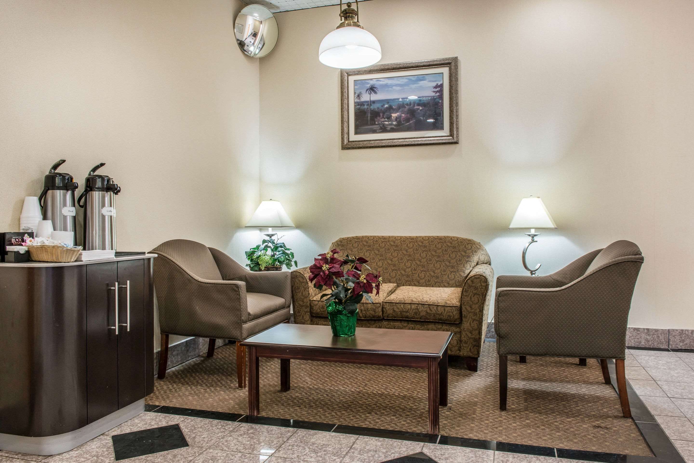 A lobby with a sofa, chairs, a coffee station, and a framed picture on the wall.