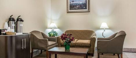 A lobby with a sofa, chairs, a coffee station, and a framed picture on the wall.