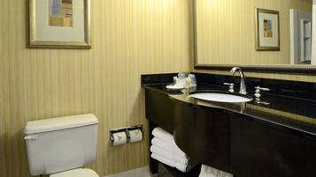 A bathroom with a toilet, sink, and mirror.