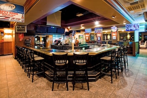 A bar area with a counter, bar stools, and various signs advertising beer specials.