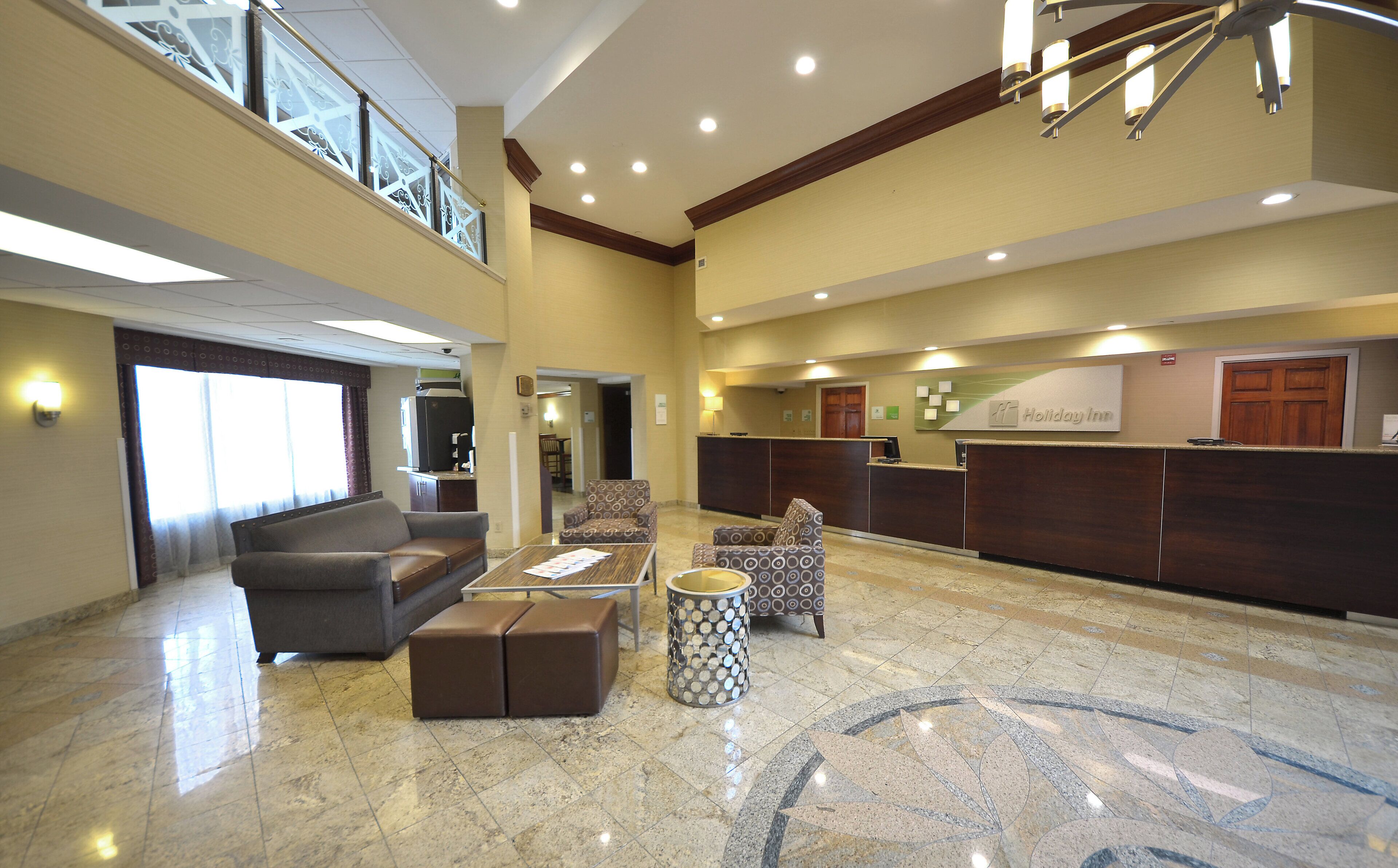 A hotel lobby with a reception desk, seating area, and a view of the upper floor.