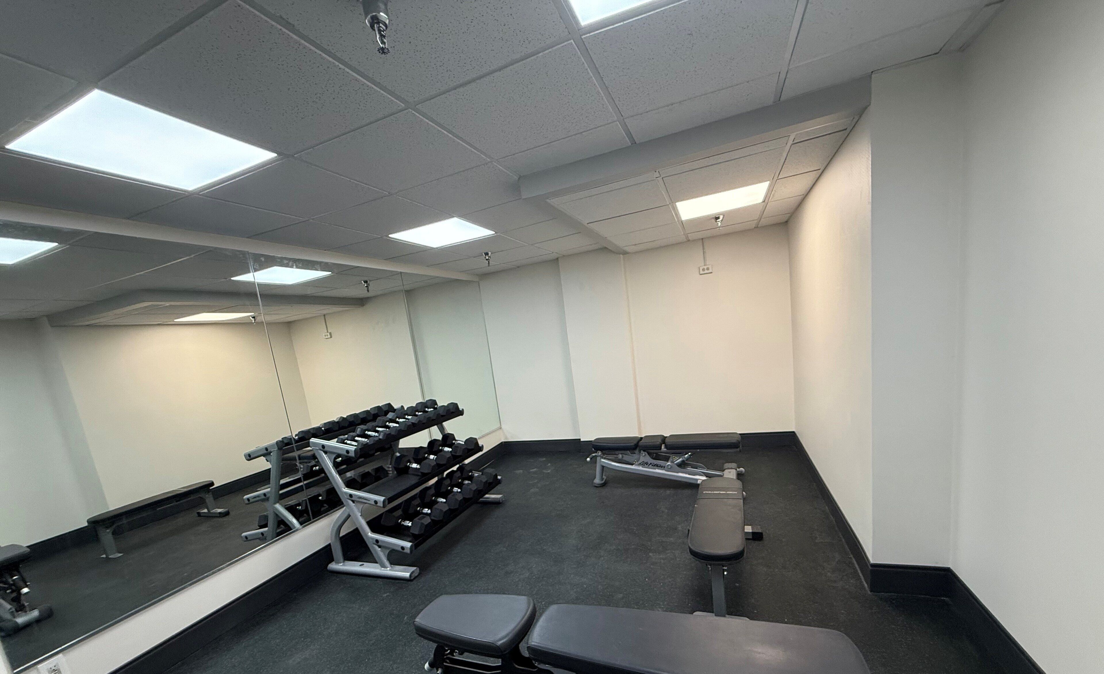 A gym with exercise equipment, a bench, and a mirror.