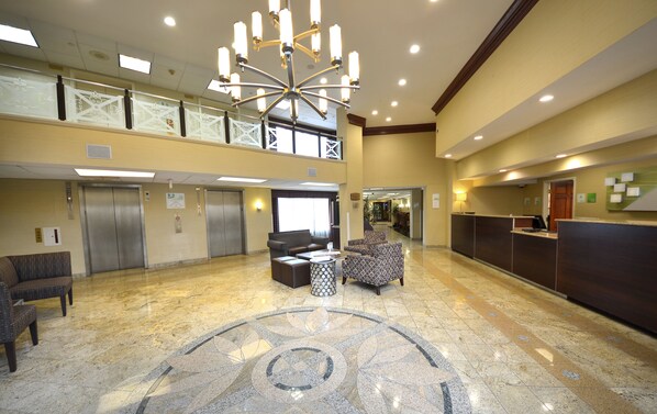A hotel lobby with a chandelier, elevators, seating area, reception desk, and a patterned floor. - Holiday Inn Washington DC-Greenbelt MD by IHG (Greenbelt)