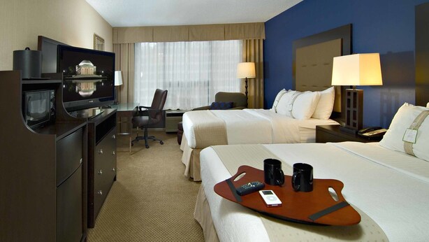Ein Hotelzimmer mit zwei Betten, einem Schreibtisch, einem Fernseher und einer Minibar.