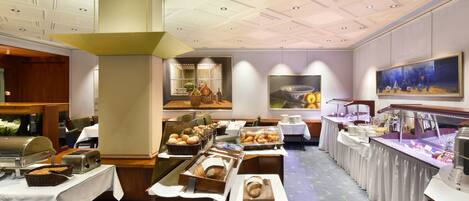 A buffet setup with various food items and a painting on the wall.
