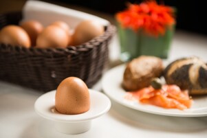 A basket of eggs, a plate with salmon, and a decorative vase with red flowers.