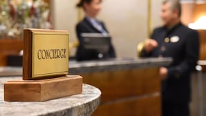A reception desk with a sign that reads "CONCIERGE" and a wooden base. - Glärnischhof by Trinity (Zürich)