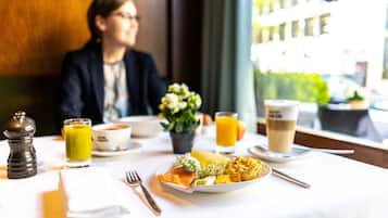 Ein Esstisch mit einem Teller Essen, einem Glas Orangensaft und einer Tasse Kaffee.