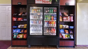 Een automaat met diverse snacks en dranken, zoals chips, frisdranken en water uit flessen.