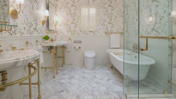 A bathroom with a marble floor, gold fixtures, a freestanding bathtub, and a glass-enclosed shower.