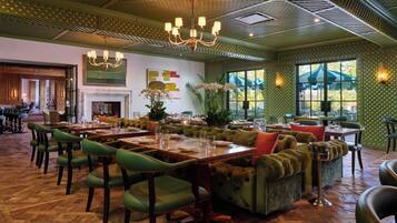 A restaurant with green upholstered seating, wooden tables, and a chandelier.