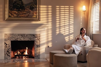An outdoor patio with wicker furniture and a glass table, overlooking a well-maintained garden and residential area. at Inn At Rancho Santa Fe