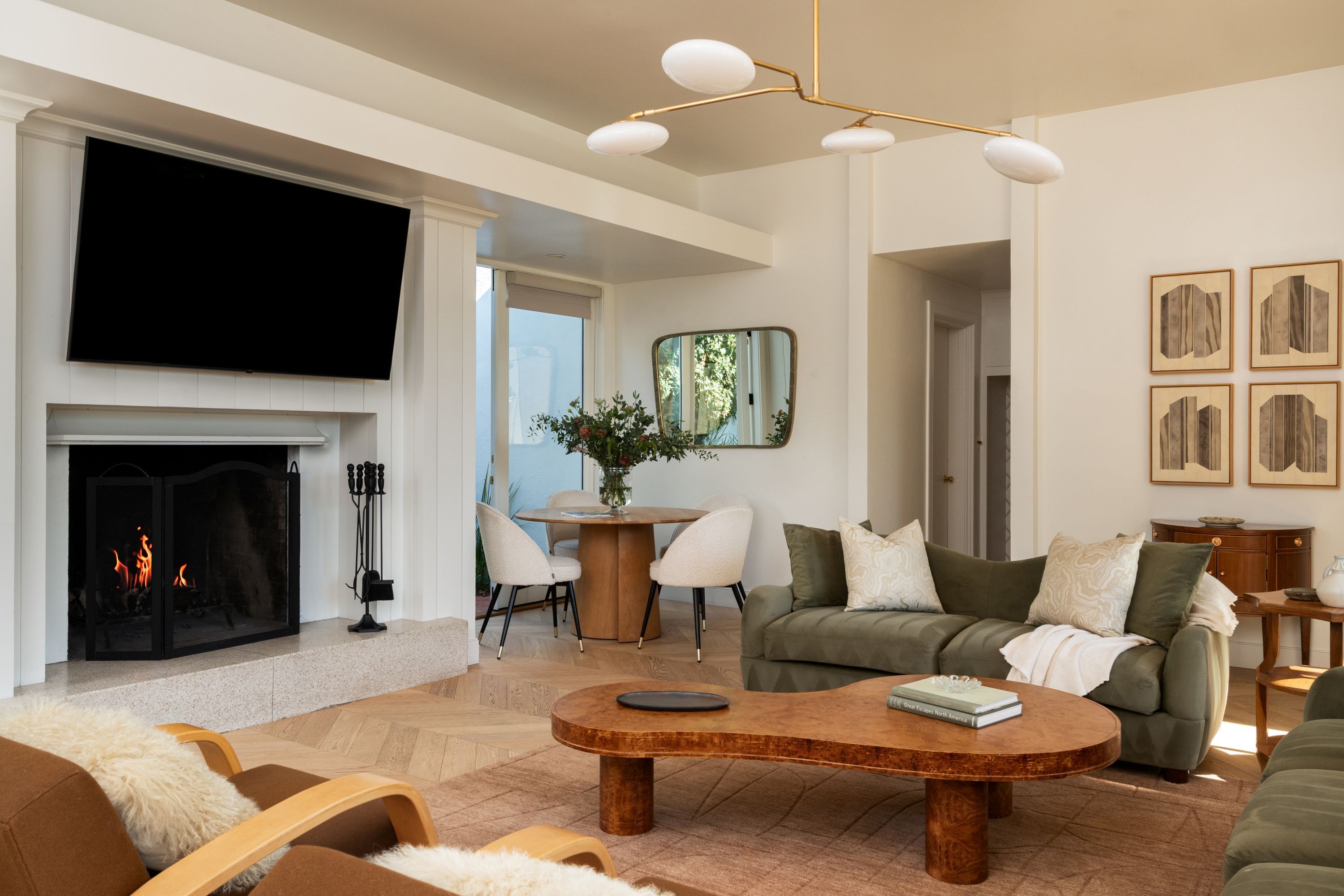Una sala de estar moderna con chimenea, un televisor de pantalla plana, una mesa de centro redonda y un sofá con almohadones decorativos.