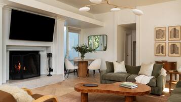 Una sala de estar moderna con chimenea, un televisor de pantalla plana, una mesa de centro redonda y un sofá con almohadones decorativos.