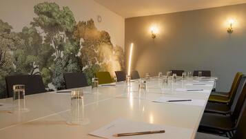 A conference room with a long table, chairs, and a mural of trees on the wall.