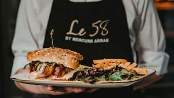 Una persona sosteniendo un plato con una hamburguesa, papas fritas y una ensalada.