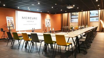 Un salón de conferencias con una larga mesa, sillas y pantallas de presentación en Mercure Hotels.