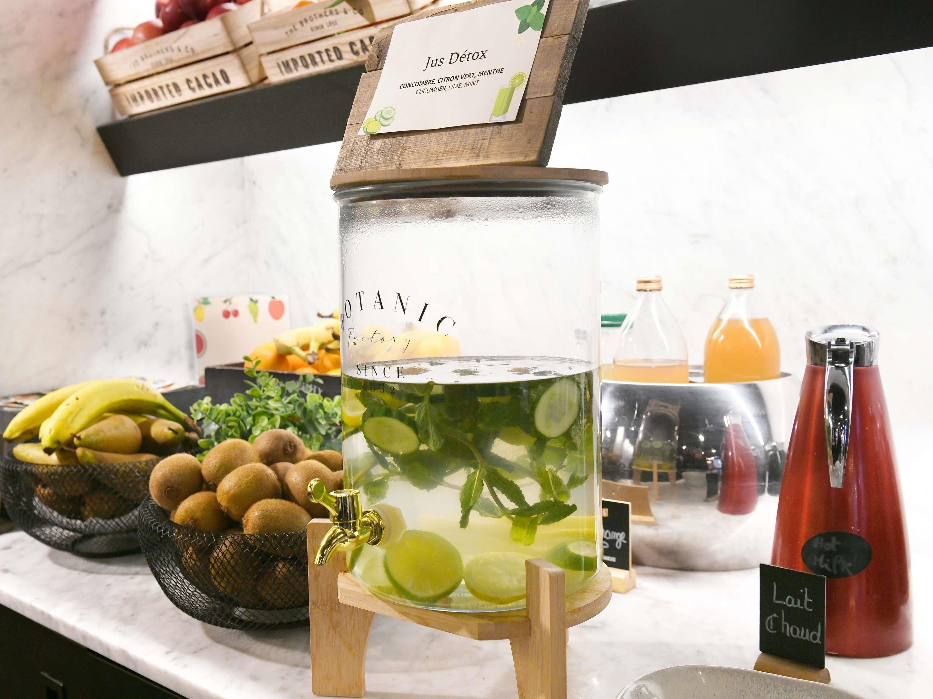 A beverage station with a large glass container, a metal tap, and a sign indicating 'Lait Chaud.'