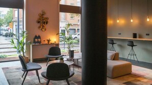A modern reception area with a large pillar, seating, a plant, and a view of the street. - Mercure Arras Centre Gare (Arras)