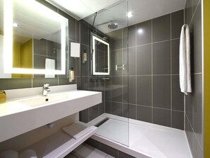 Une salle de bain moderne avec un lavabo blanc, un miroir et une douche.