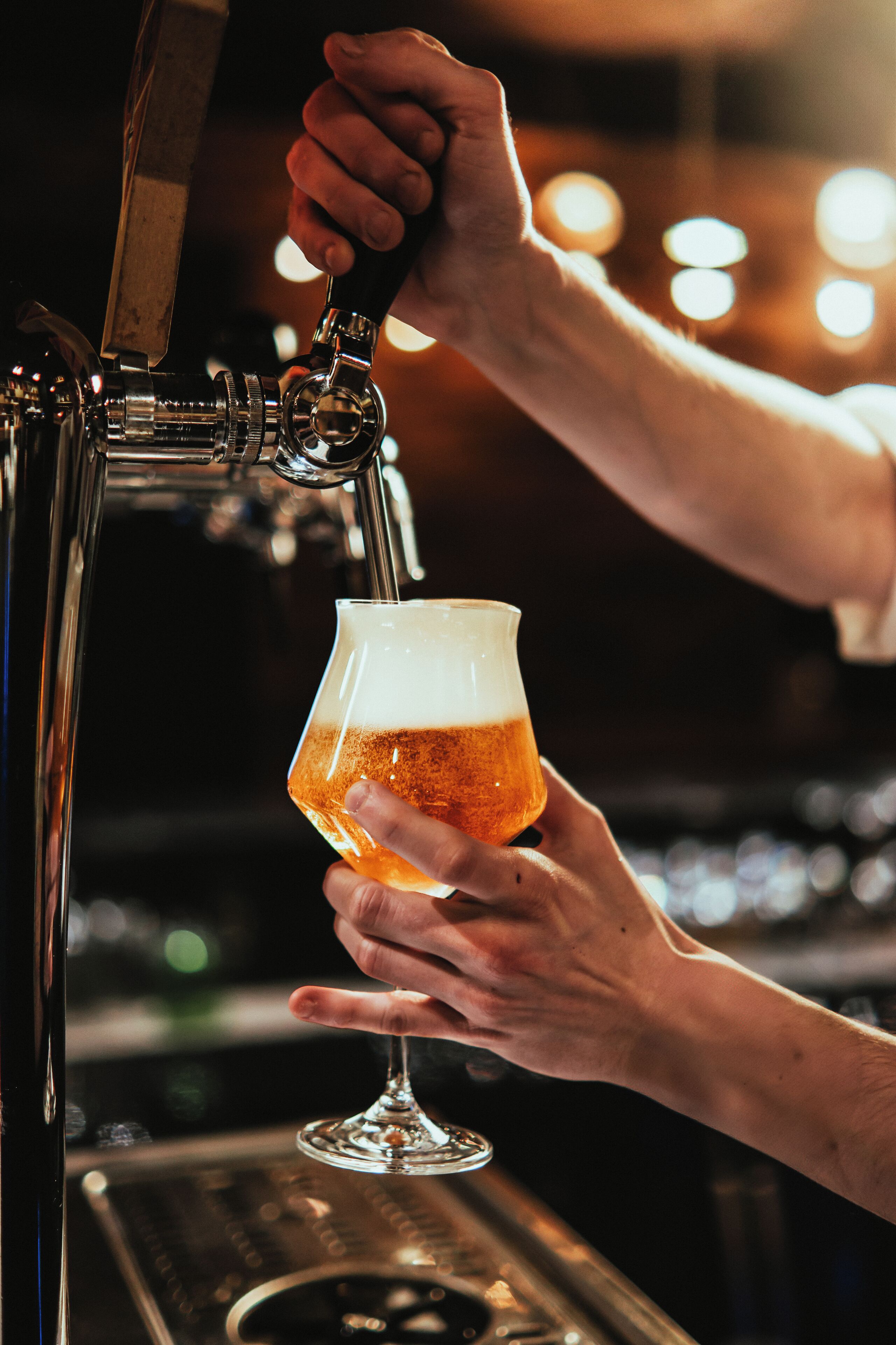 En person som häller upp öl i ett glas från en tappkran.