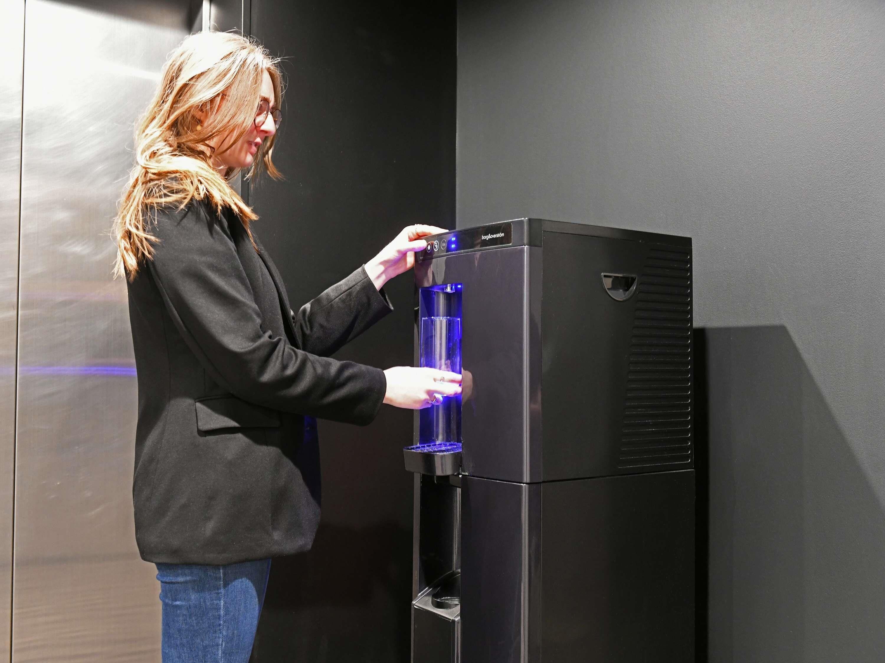 A person interacting with a black water dispenser.