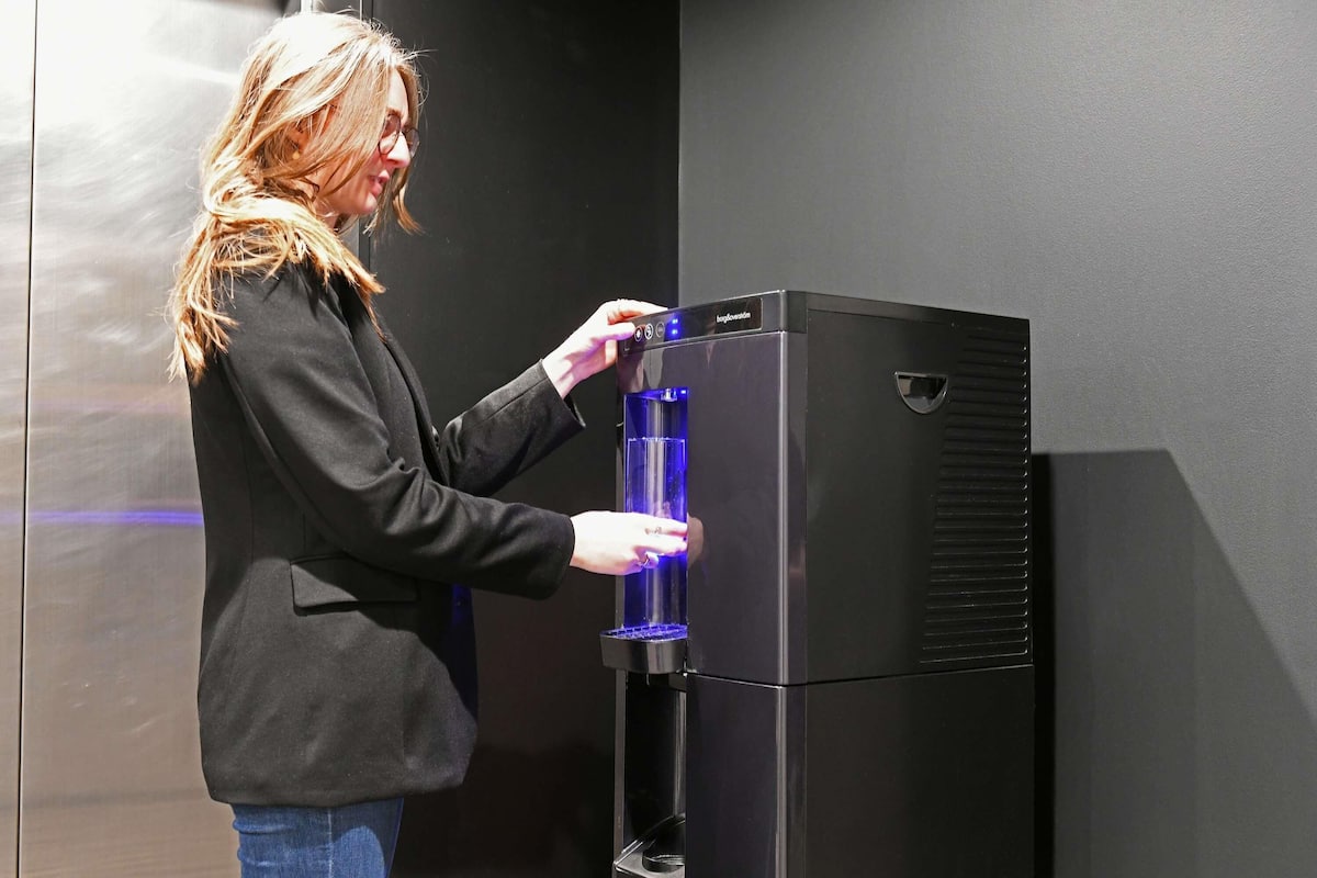 A person interacting with a black water dispenser.