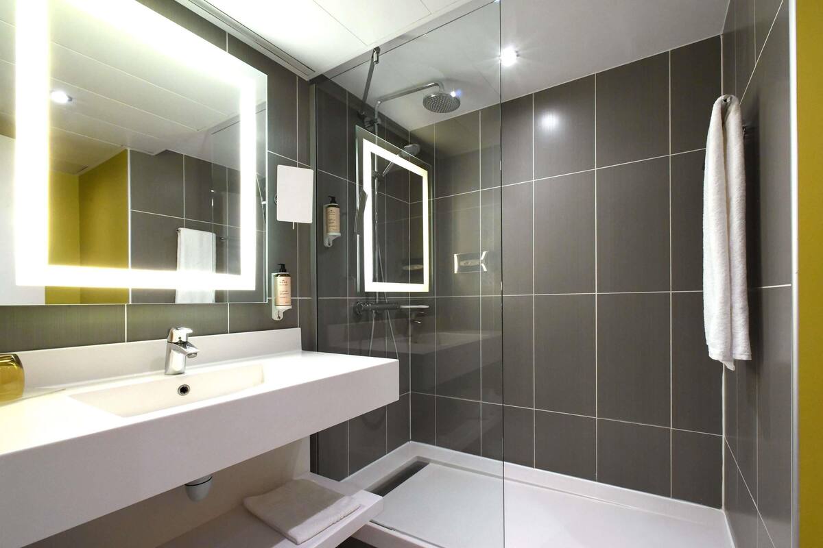 A modern bathroom with a white sink, mirror, and shower.
