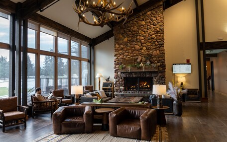 A spacious lobby with a stone fireplace, leather seating, and large windows offering a view of the outdoors.