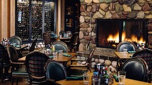 Un restaurante con paredes de piedra, una chimenea y una bodega visible a través de una puerta de cristal.
