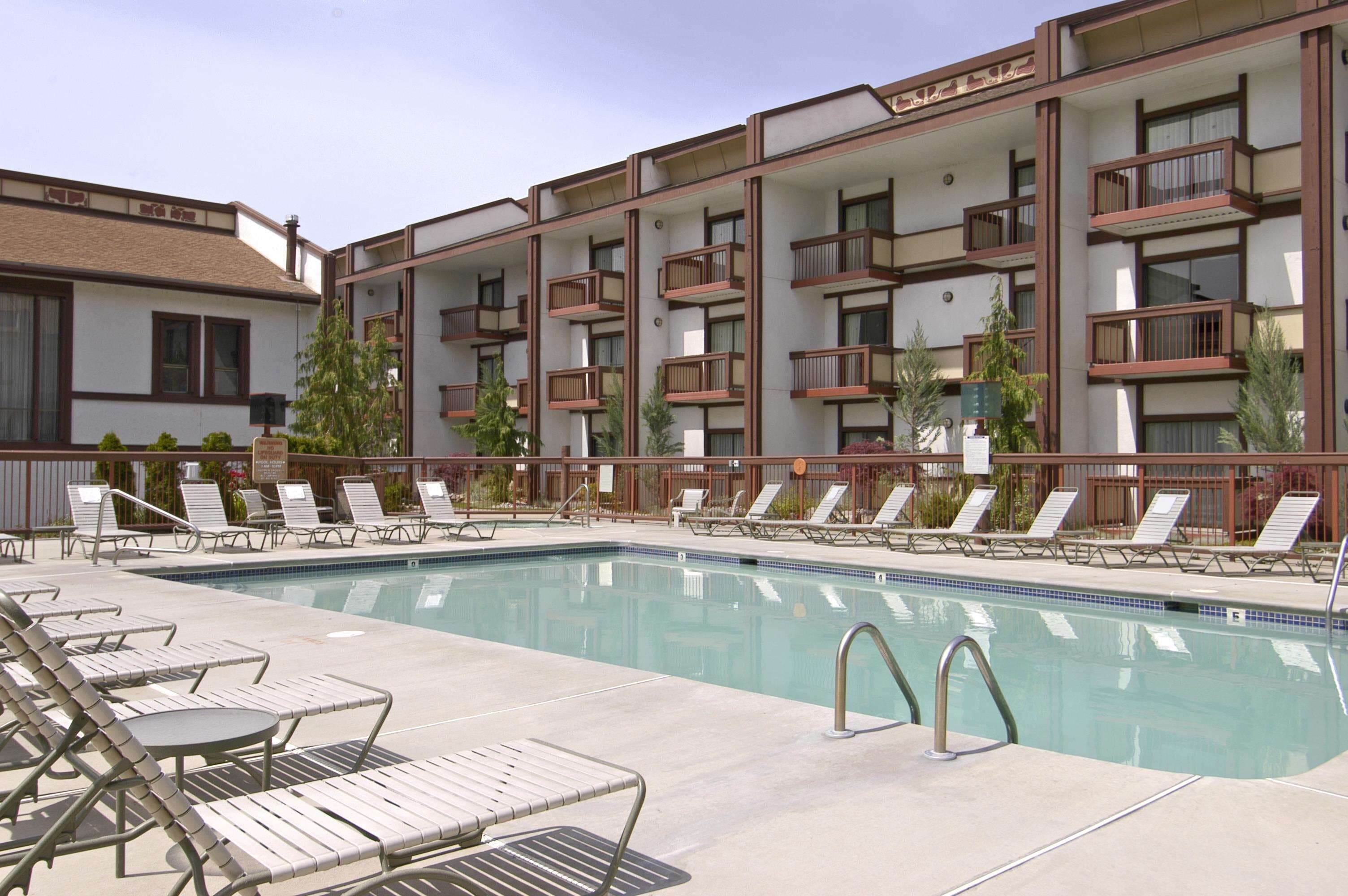 A swimming pool with lounge chairs and a building with balconies.