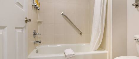 A bathroom with a bathtub, toilet, and a shower area.