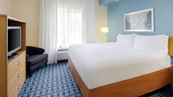 Habitación de hotel con una cama grande, televisión, escritorio y ventana con cortinas.
