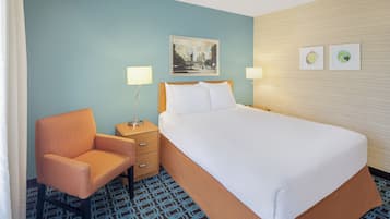 Une chambre d’hôtel avec un lit, une chaise, une table de chevet et un tableau accroché au mur.
