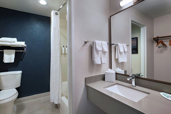 A modern bathroom with a white sink, a large mirror, and a shower area.