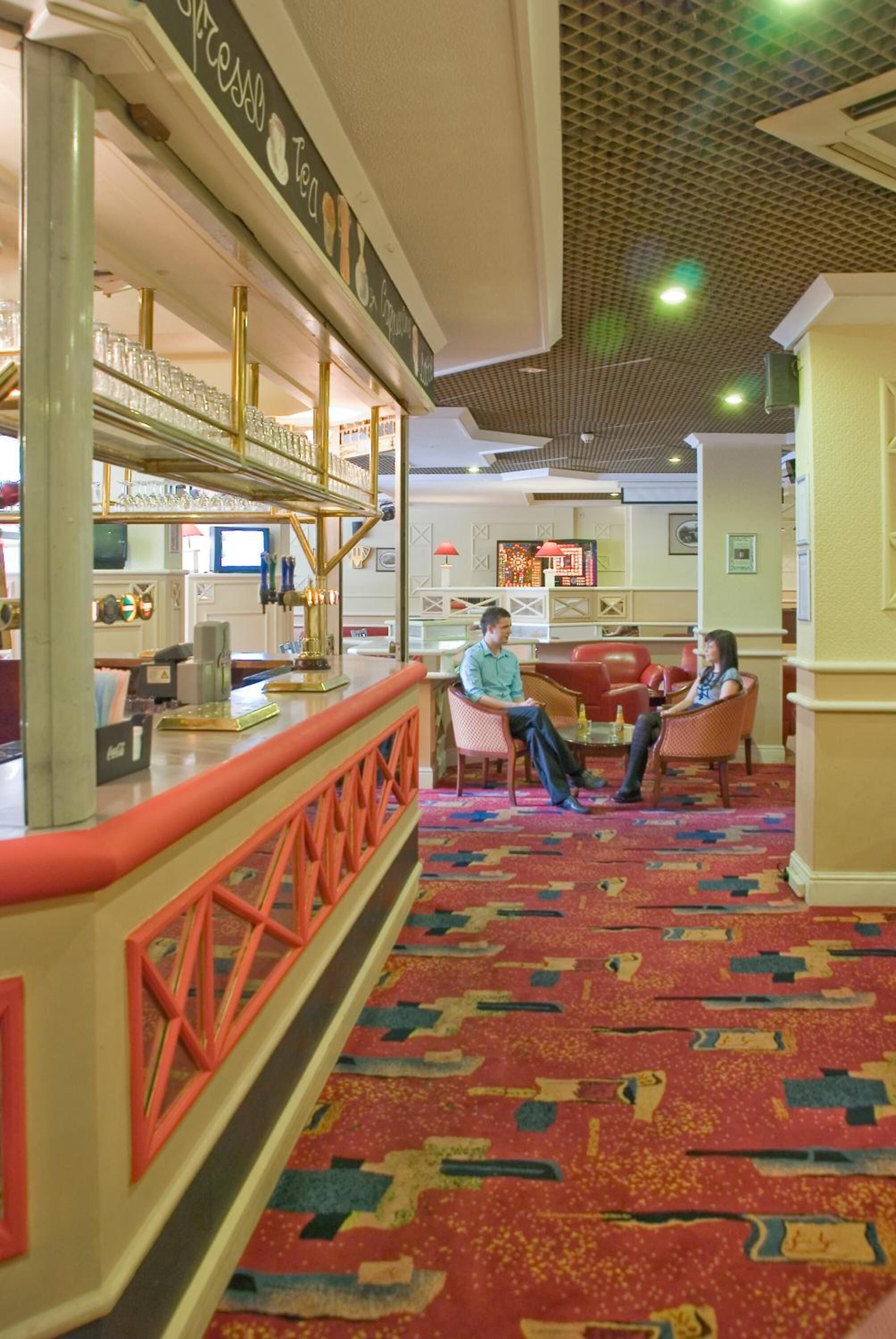 A lobby with a reception desk, seating area, and a patterned carpet.
