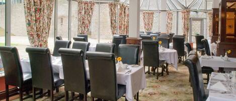 A restaurant with a glass roof, floral curtains, and tables set for dining.