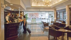 Un vestíbulo de hotel con mostrador de recepción, zona de estar y una araña.